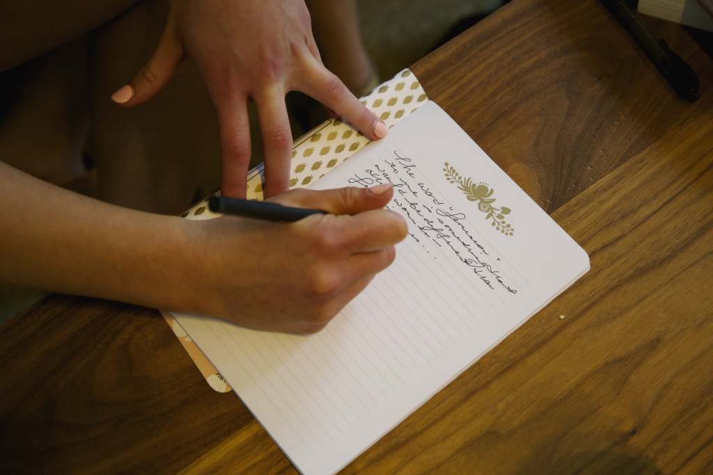Writing-notebook-hands-pen-wood-table