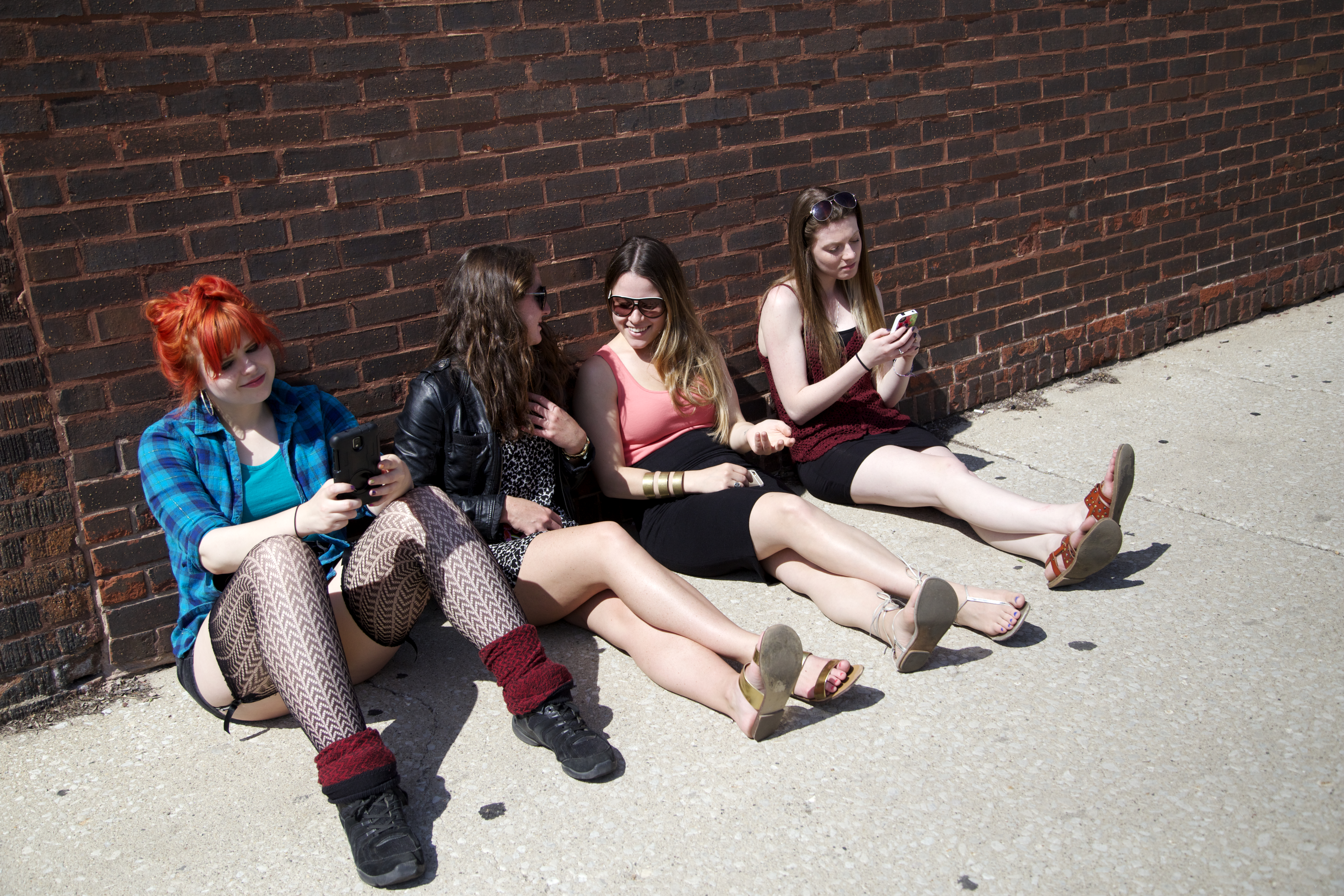 women-brick-wall-sitting-texting